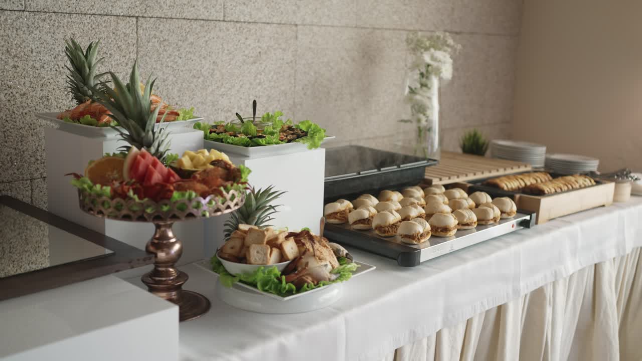 assorted buffet with fruit platter mini burgers and savory appetizers on white table