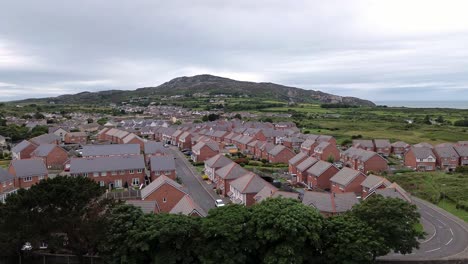 aerial view orbit across modern red brick housing neighbourhood under holyhead mountain in wales