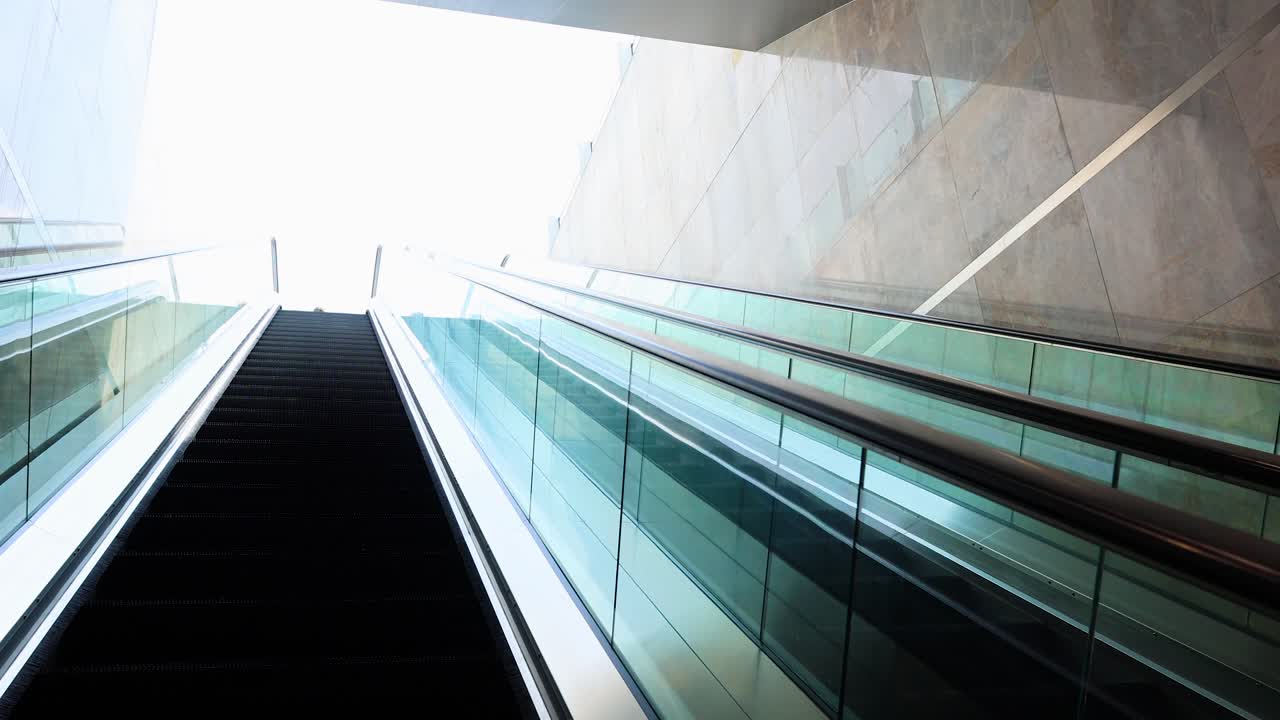 En 30-sekunders video, der viser en rulletrappe på vej op i et indkøbscenter i Bangkok, med moderne arkitektur og lyst dagslys.