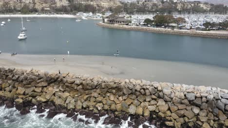 beautiful-sweeping-trucking-pan-of-dana-point-harbor-filled-with-paddleboarders-boats-and-fun-things-on-a-pretty-day-with-blue-skies-in-california