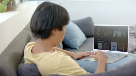 teenage asian boy browses on his laptop at home