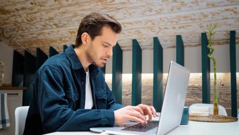 joven independiente que trabaja en la computadora en la cocina. empresario concentrado en el desarrollo de nuevos proyectos mientras trabaja en la laptop en casa.