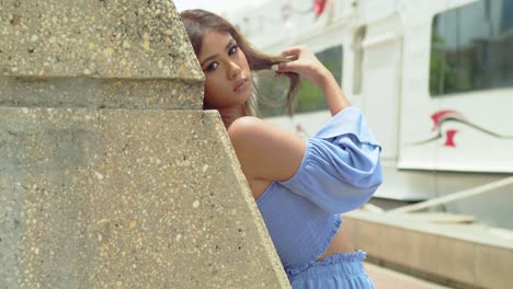 An-inter-island-ferry-in-the-background-a-model-looks-over-her-right-shoulder-while-leaning-on-a-post