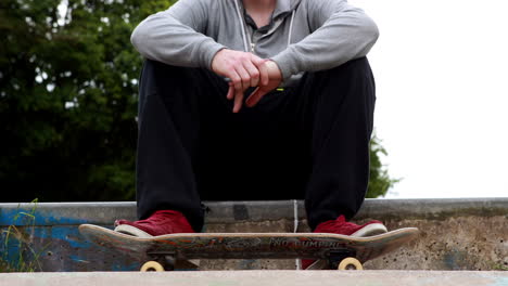 young skateboarder sitting at the outdoor skatepark