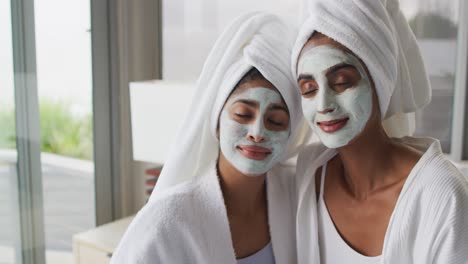 Video-of-relaxed-diverse-female-friends-moisturizing-with-face-masks-in-bathroom