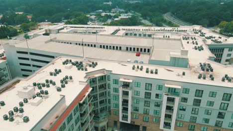 Drone-footage-reveal-of-an-enormous-apartment-complex-building,-with-a-parking-garage-on-top