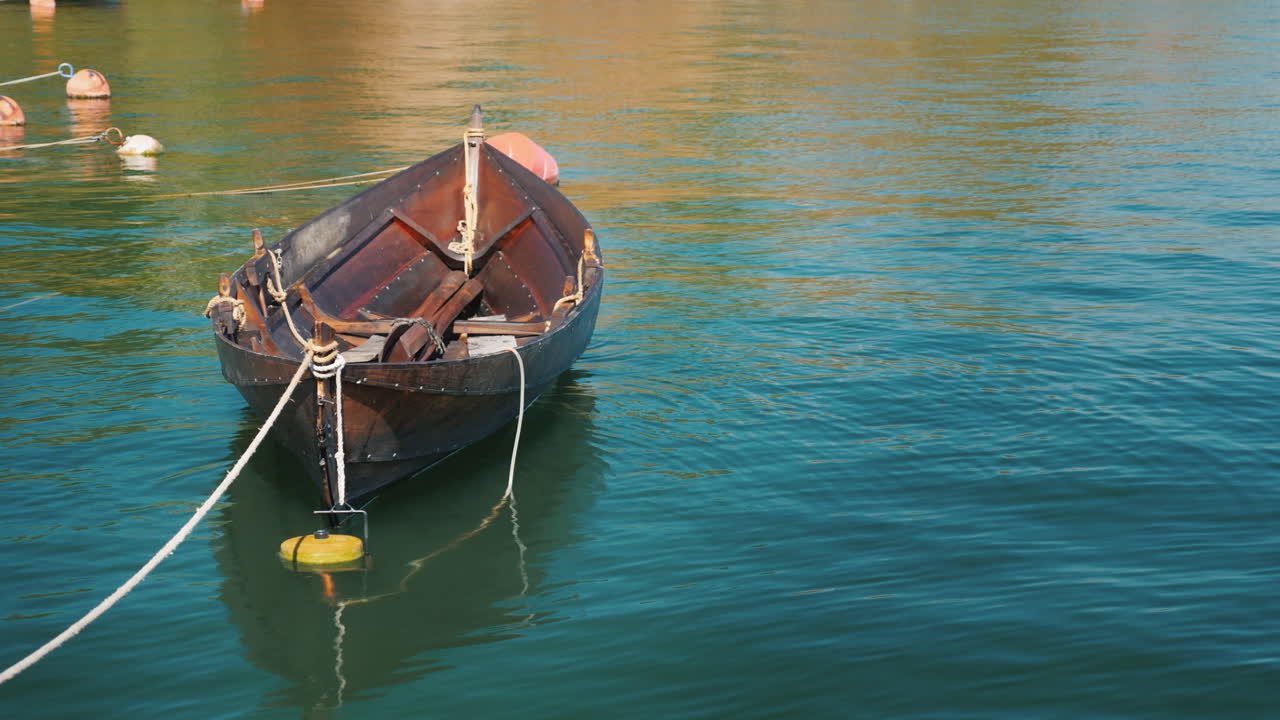 un barco de pesca está amarrado en la orilla balanceándose lentamente sobre una ola en un claro día de verano 4k video