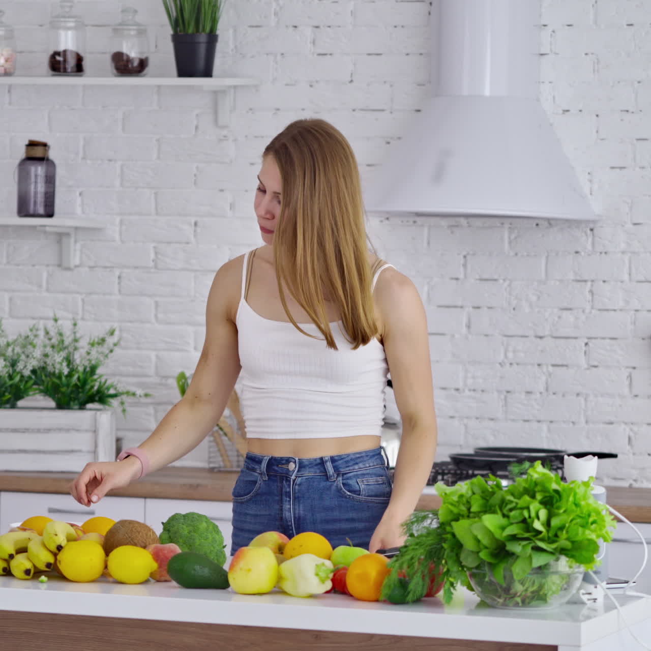 Young woman with fresh vegetables and fruit indoors. Vegetarian female eating organic food in the modern kitchen at home. Dieting concept.