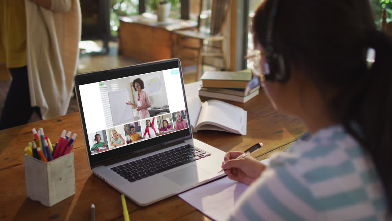 Schoolgirl using laptop for online lesson at home, with diverse teacher and class on screen