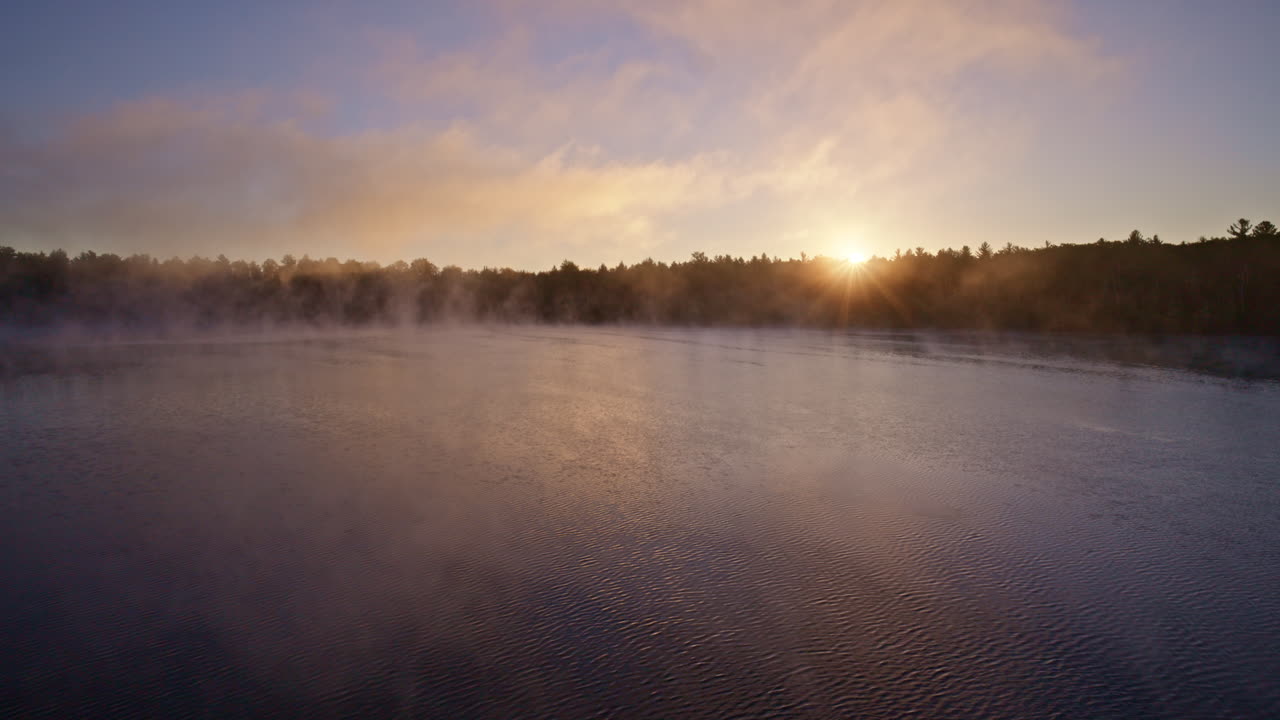 Drone shot capturing mist lifting off the water at dawn