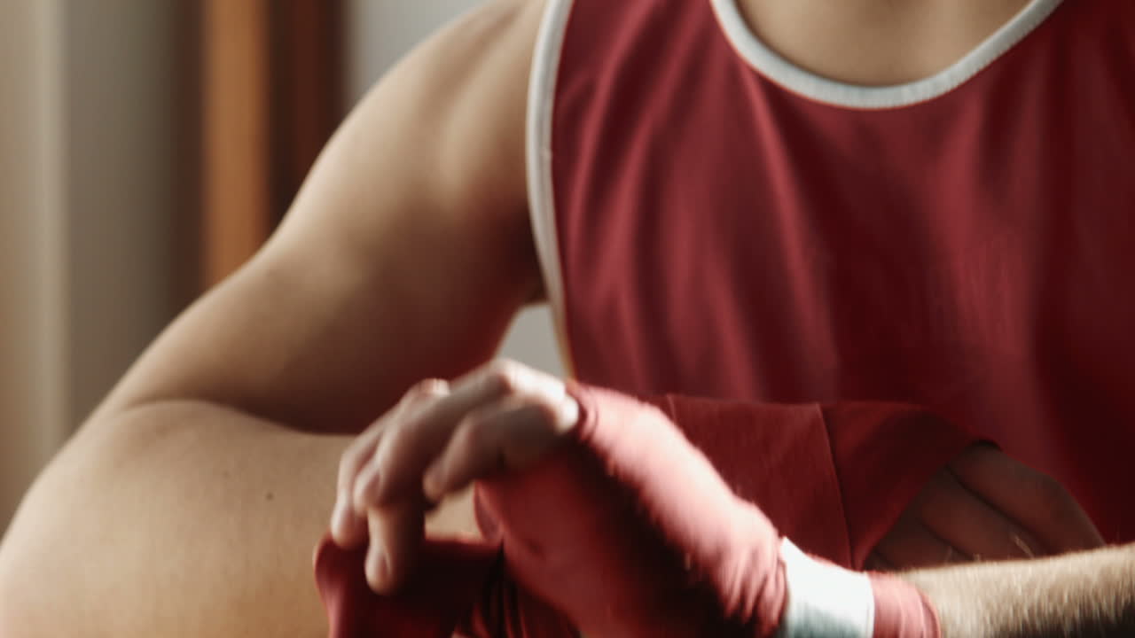 The Young Boxer Pulls Red Bandage on Hands