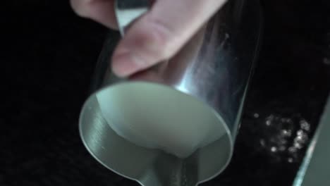 putting some milk into the glass of coffee in circular motion to make a design. -medium shot