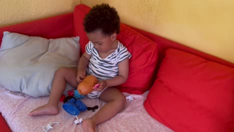 cute two year afro european child happy playing with mr potato at home