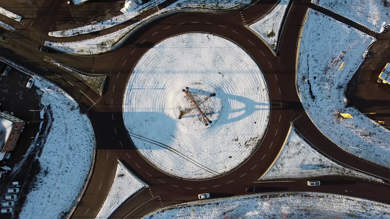 Bird's eye view above snow covered round about traffic circle at midday, long shadows cast on snow