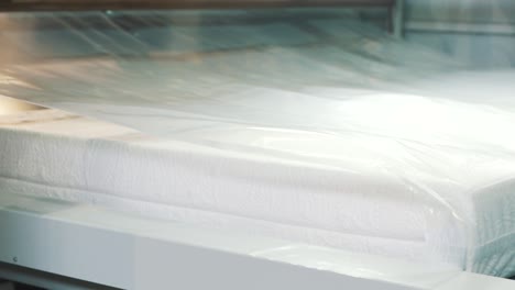 primer plano de un colchón empaquetado en una envoltura de plástico en una línea de montaje de fábrica