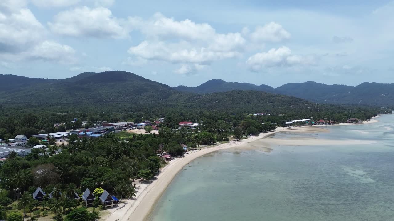 Aerial footage of Thong Sala Beach with a wide sandy shoreline, turquoise sea and lush tropical scenery on Koh Phangan island, Thailand