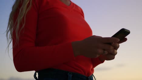 Woman-using-mobile-phone-on-beach-at-dusk-4k