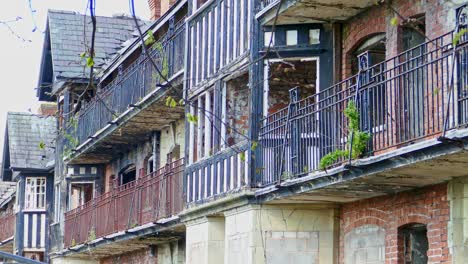 tudor style flats with wrought iron railings foliage growing out of the disused building