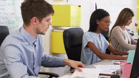 young man and woman discussing document in open plan office