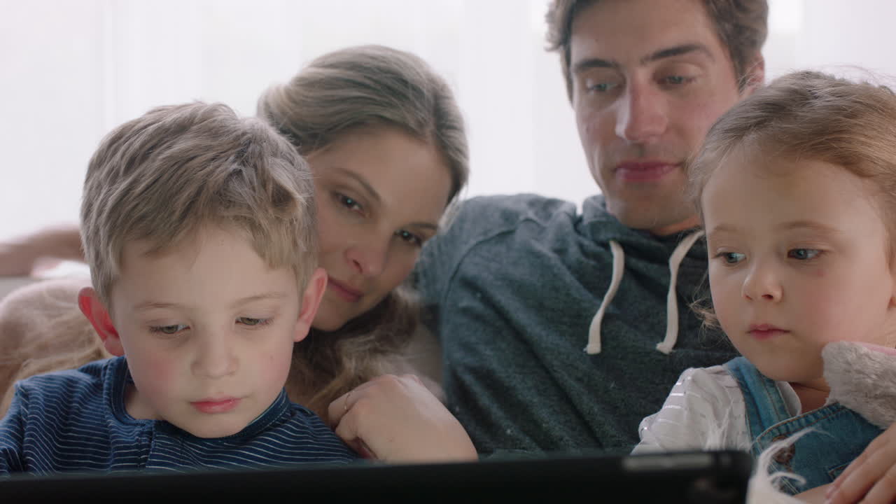 famiglia felice che usa il tablet a casa madre e padre con i figli che guardano l'intrattenimento giocando a un gioco su un dispositivo touchscreen imparando a divertirsi insieme filmati in 4k