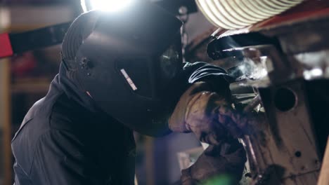 lavoratore maschile in una fabbrica di saldatura con occhiali protettivi. saldatura in un impianto industriale. slow motion.