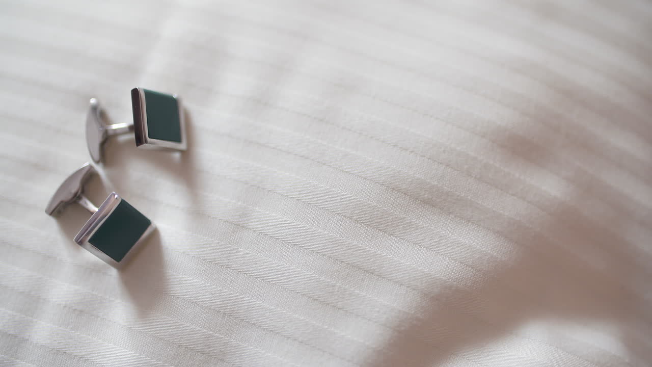 Eleganti gemelli verdi e argento su tessuto bianco.