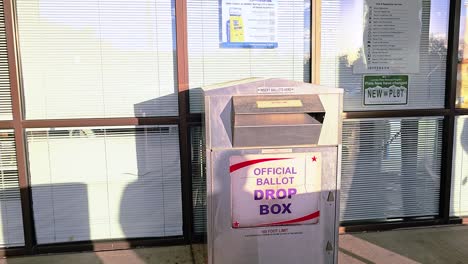 man votes by casting mail-in ballot letter in slot at voting booth with offical ballot drop box sign for democratic government election in presidential race