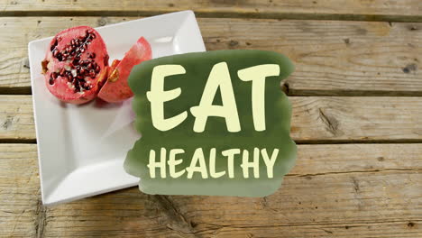 animation of eat healthy text over pomegranate on plate on table