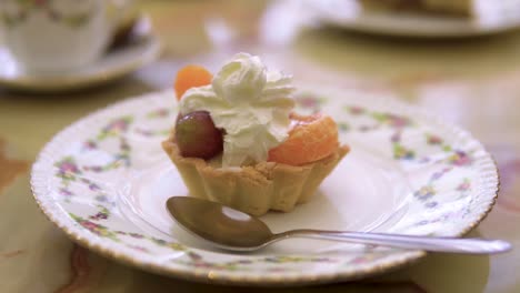 fruta de galleta con crema encima como postre para un descanso de café servido en un plato antiguo con una cuchara a cámara lenta