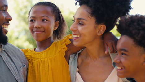 Close-Up-Portrait-Of-Smiling-Family-Standing-In-Summer-Garden-Or-Countryside-Smiling-At-Camera