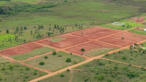 gridded farmland plots with reddish soil in an open countryside landscape, candelaria, misiones, argentina.