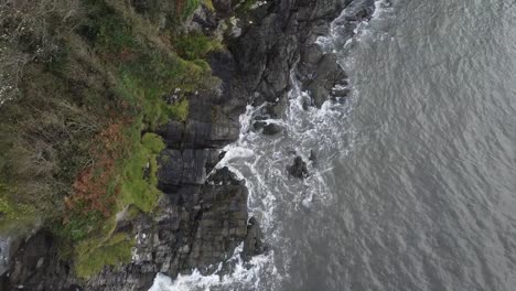 Luftdrohne-Aus-Der-Vogelperspektive-Von-Wellen,-Die-An-Einer-Felsigen-Und-Sandigen-Küste-Mit-Wald-Auf-Den-Klippen-Zusammenbrechen---Lee-Bay,-Strand,-Ilfracombe,-Devon,-England