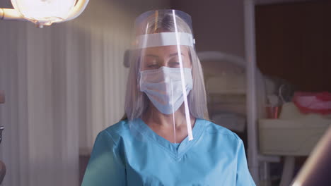 medical professional in scrubs with face mask and shield