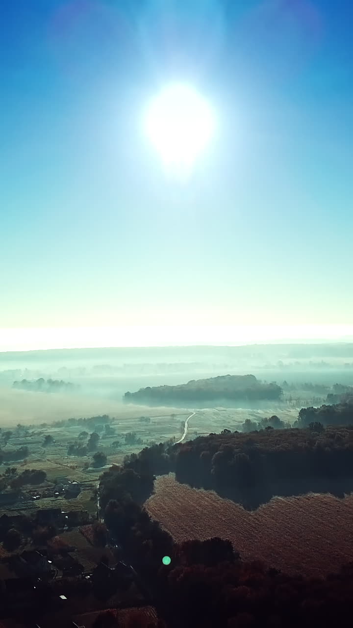 Morning sunrise in the village on misty weather. Panoramic view of beautiful dawn over the roofs of the houses and big forest. Aerial View. Soft sun light. Slow motion. Vertical video