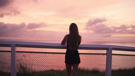 Female-standing-on-ocean-path-at-lookout-in-vibrant-sunrise