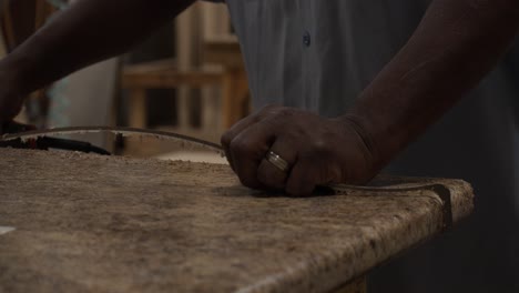 skilled carpenter trims veneer from the edges of a new kitchen counter in his workshop