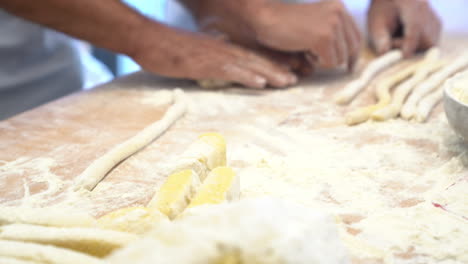 manos humanas hacen y modelan un trozo de pasta en una mesa hecha