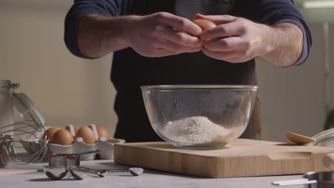 close up of man in kitchen at home adding ingredients to bowl to bake cake 1