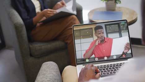 african american businessman using laptop for video call with african american business colleague
