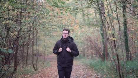 Captivating-footage-of-a-young-European-man-gracefully-running-in-slow-motion-through-a-mesmerizing-autumn-forest,-with-a-deep,-intent-gaze-directed-towards-the-distant-horizon