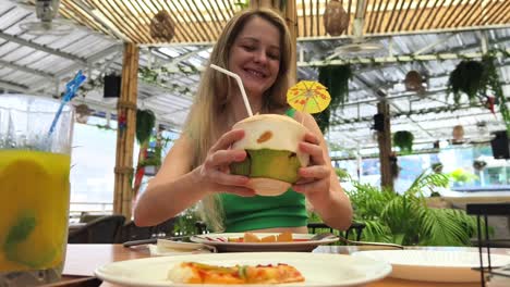 mujer disfrutando de una bebida de coco y comida al aire libre
