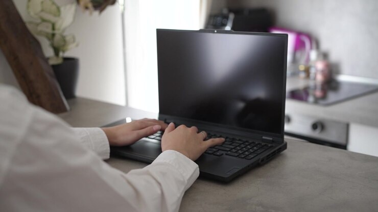 Vista dettagliata di una donna che scrive al computer portatile in interni. Concetto di lavoro freelance moderno, comunicazione aziendale e tecnologia per la produttività