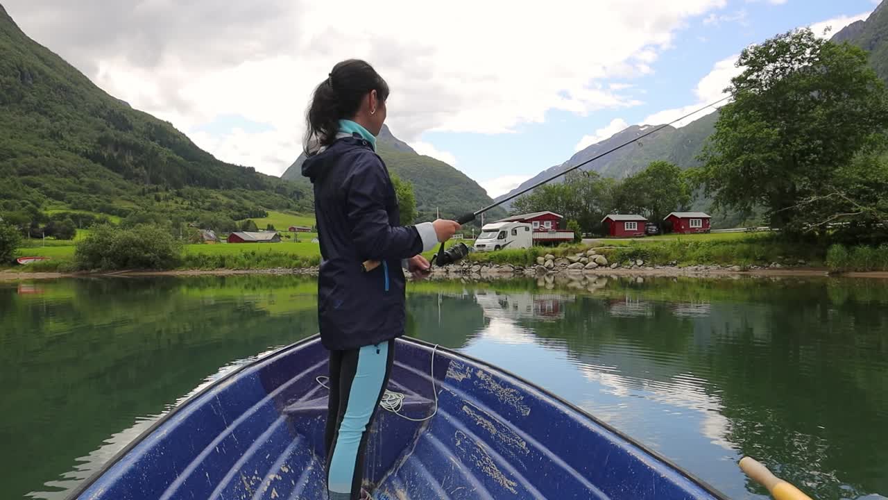 la mujer en el barco atrapa un pez en el giro en noruega.