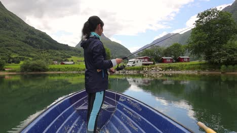 Una-Mujer-En-El-Barco-Pesca-Un-Pez-Girando-En-Noruega.