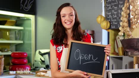 Portrait-of-a-female-staff-holding-a-open-sign