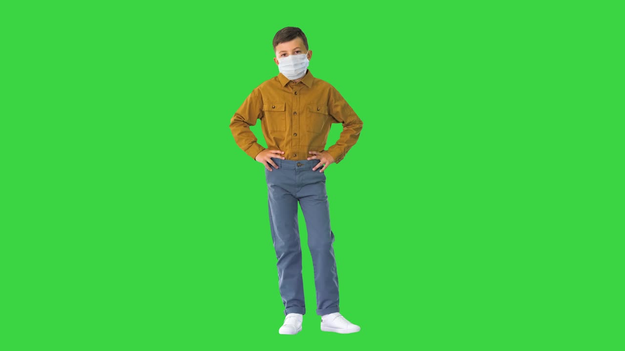 niño con máscara protectora mirando a la cámara en una pantalla verde, llave de croma