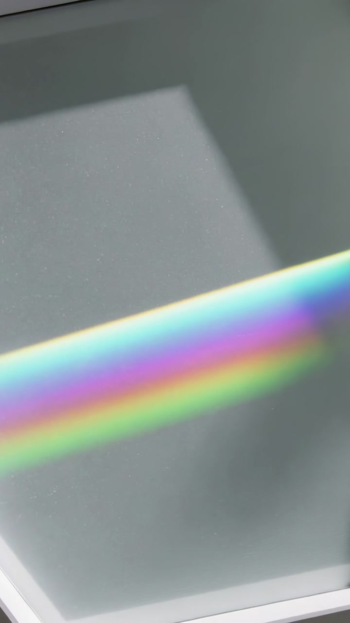 Vertical video: Shifting color band moving across pale panel and trim, sunlight bending via window