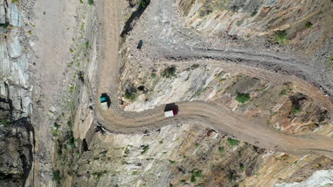 dramatic drone shot of vehicles passing each other on fairy meadows road in pakistan, second deadliest highway in the world, downward angle aerial