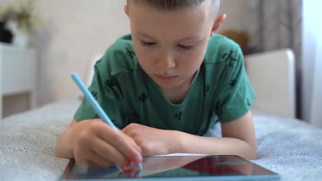 a school-age boy draws with a stylus on a digital tablet