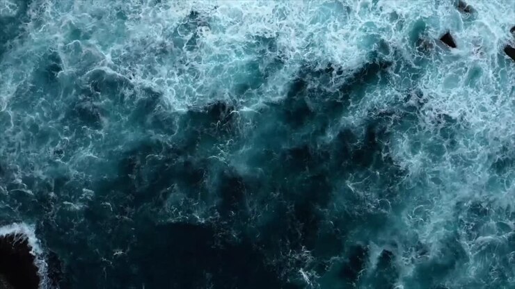Aerial View of Powerful Ocean Waves Crashing on Rocky Coastline